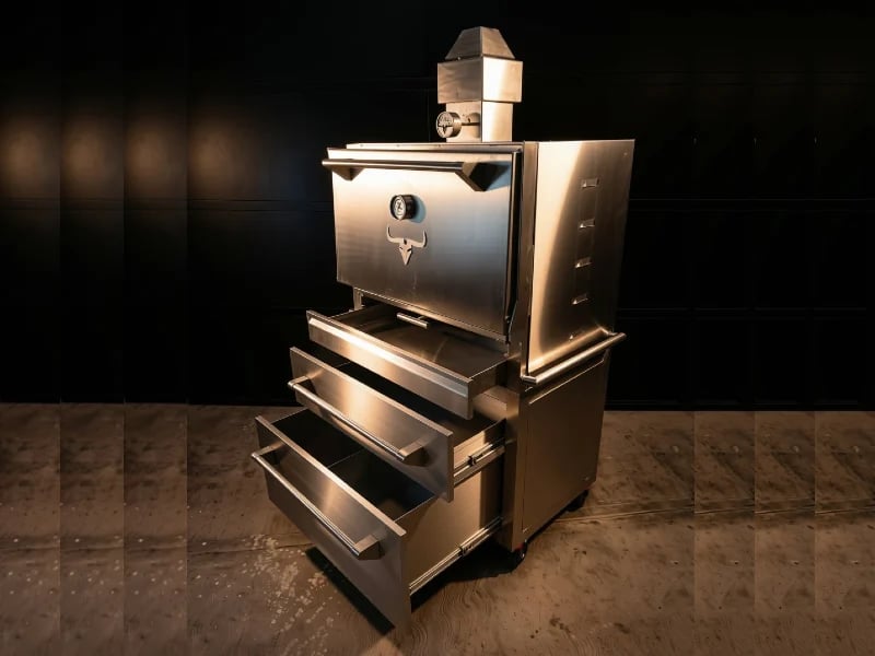 Horno de brasa Malevo en acero inoxidable sobre una encimera de granito con fondo oscuro
