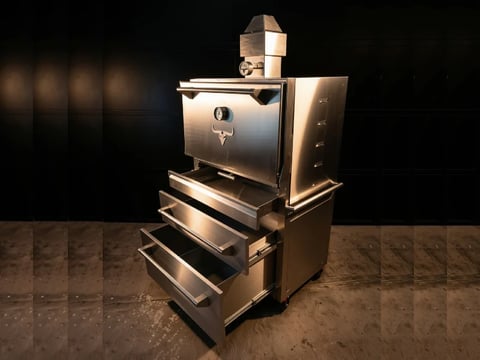 Stainless steel espresso machine with multiple drawers stacked on a granite counter against a dark background